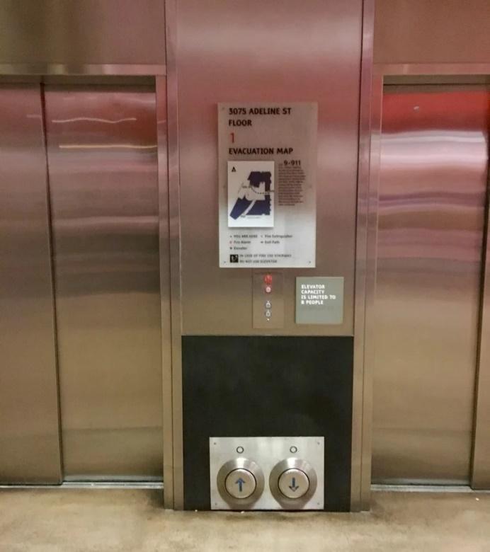 Dva dizala širokih vrata između kojih se nalaze kontrole velikih dimenzija postavljene u razini poda 