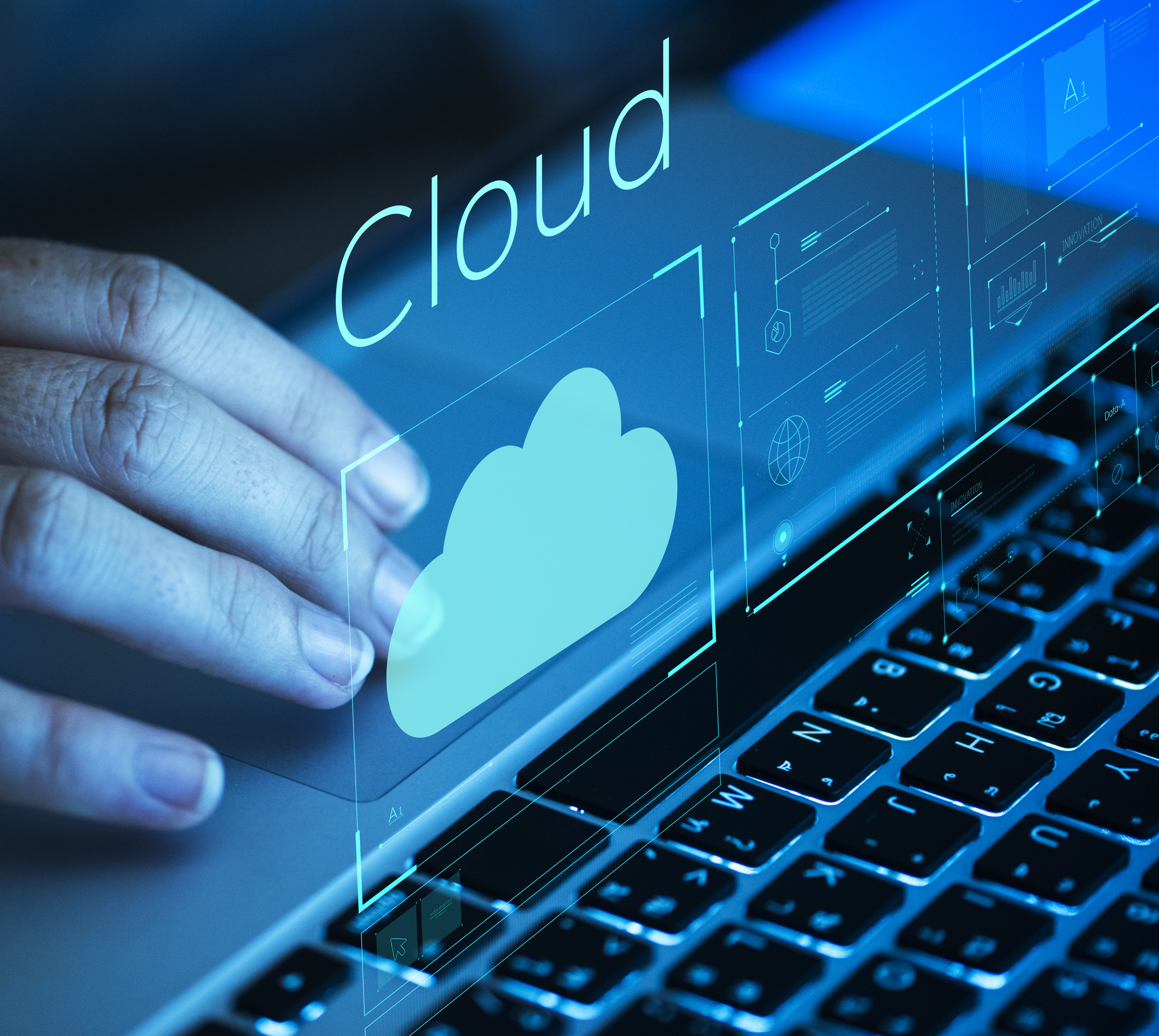 Ruka dodiruje touchpad prijenosnog računala s prikazom digitalnog oblaka i natpisom „Cloud“ u plavom svjetlu