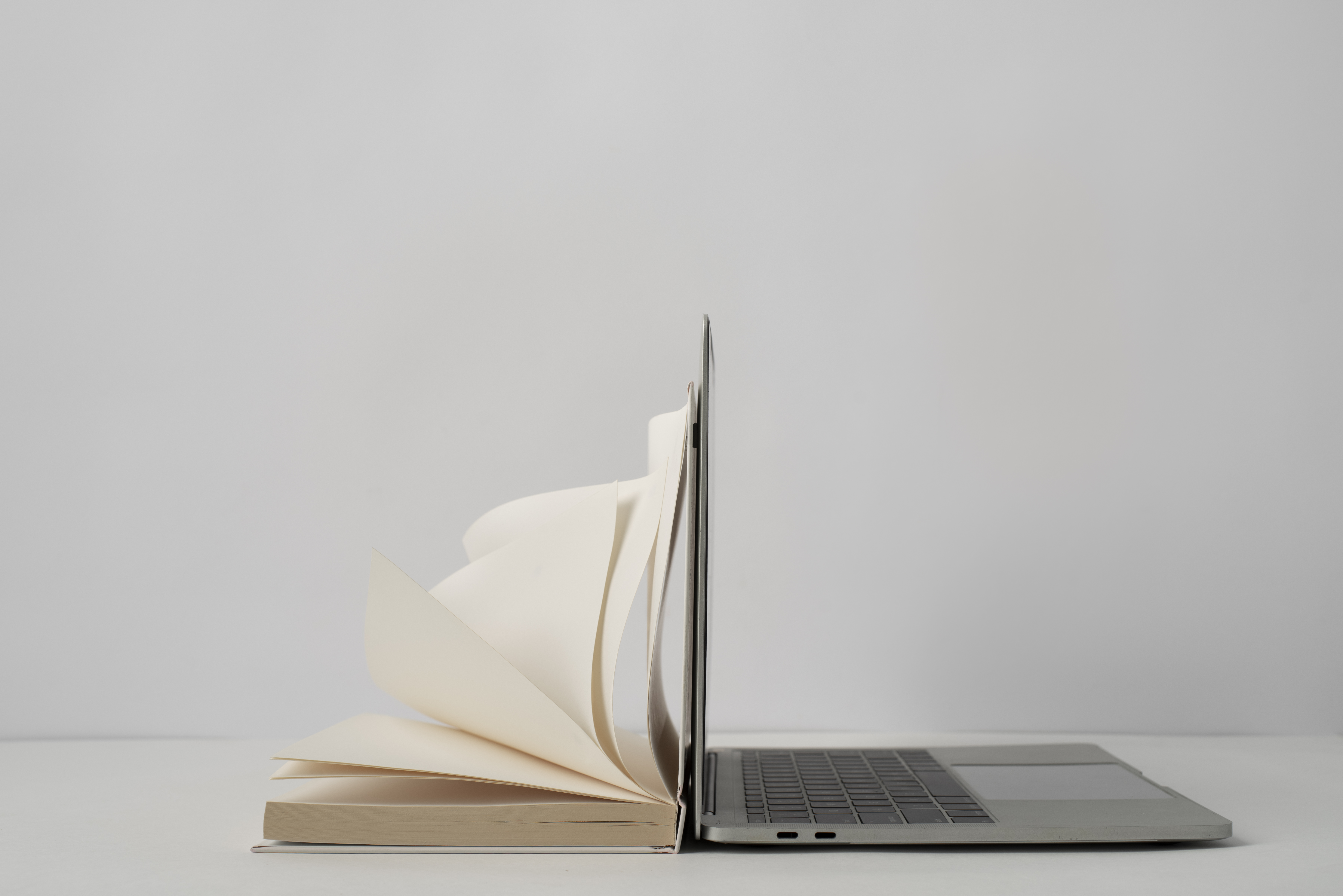 A laptop and a book leaning against each other