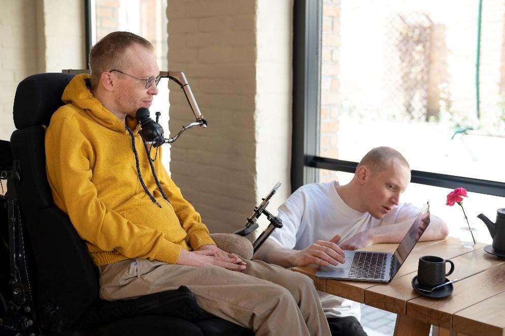 A wheelchair user with a microphone positioned by an adjustable swing-away mount.

AI-generated content may be incorrect.